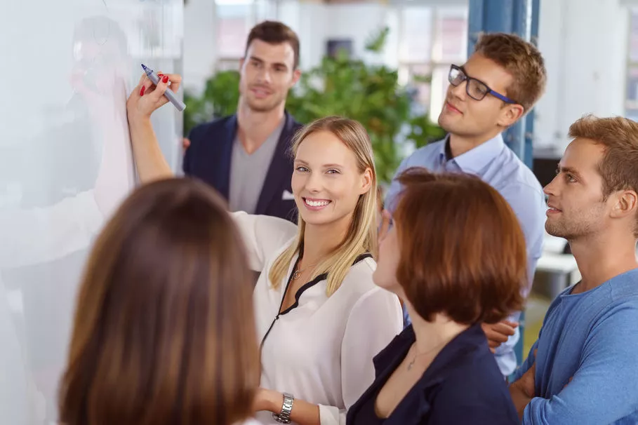 Frau am Whiteboard umringt von Zuhöhrern